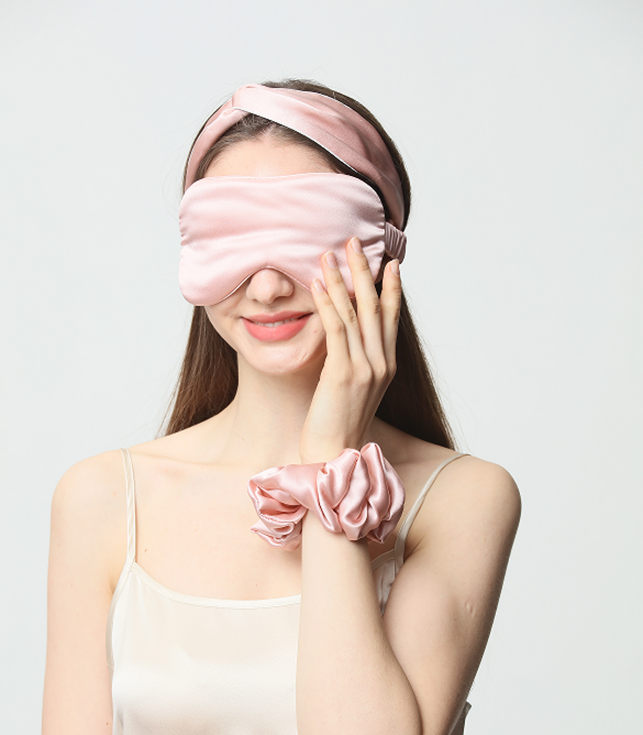 Pink silk eye mask and scrunchie styled for a self-care routine