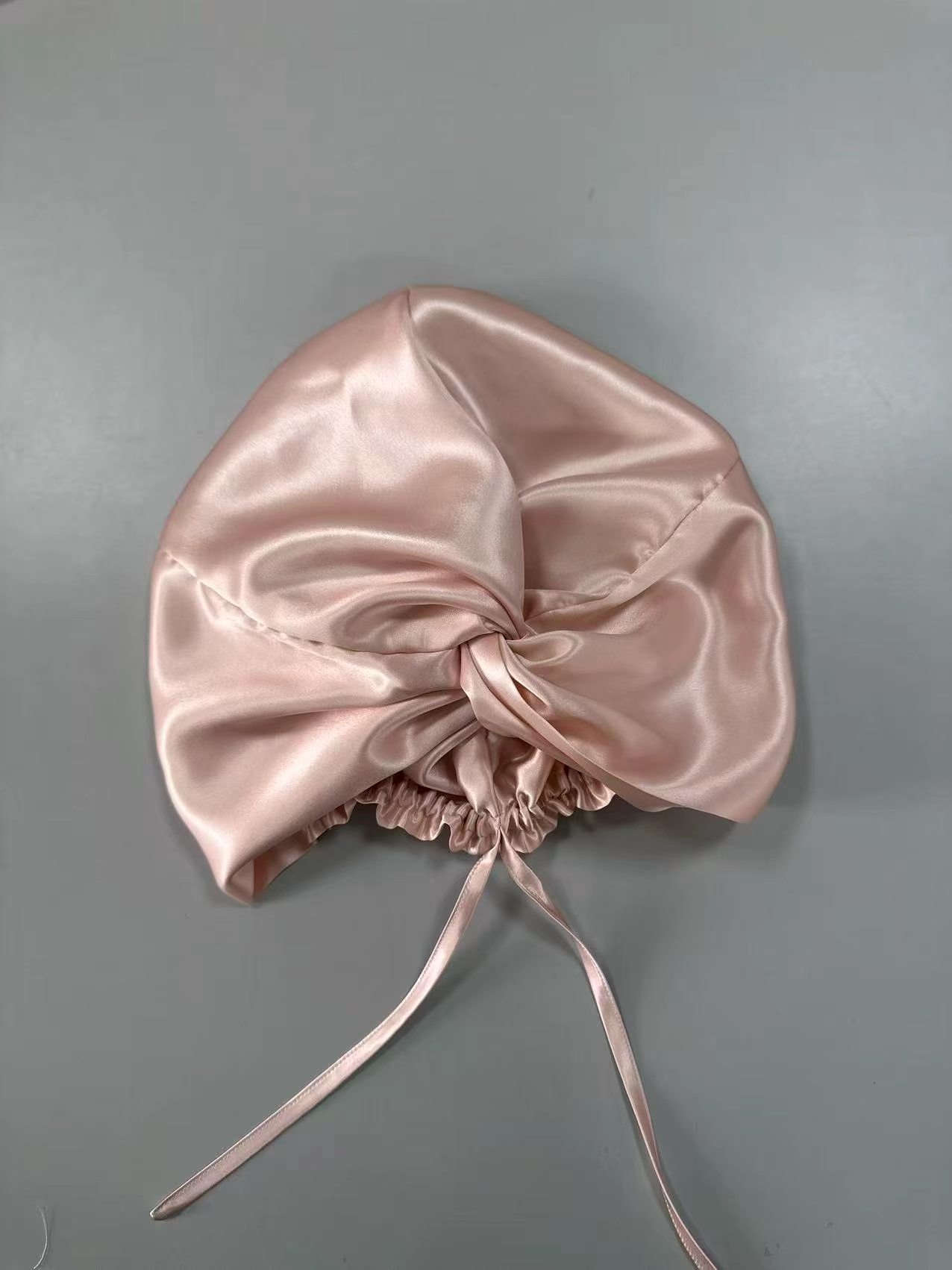 Pink silk hair wrap shown from the front with its tie closure